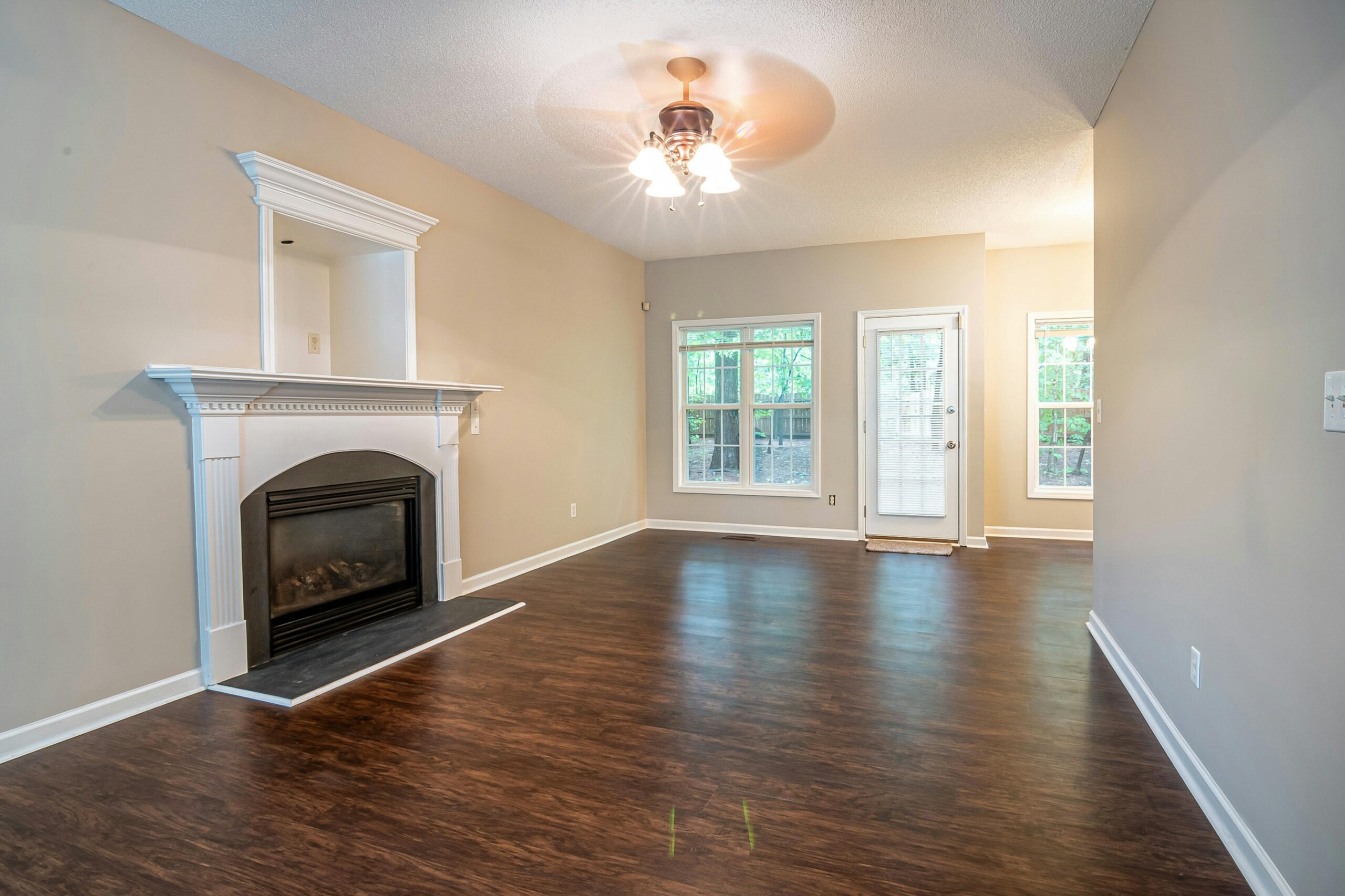Spacious and bright living room with hardwood floors, fireplace, and ceiling fan.